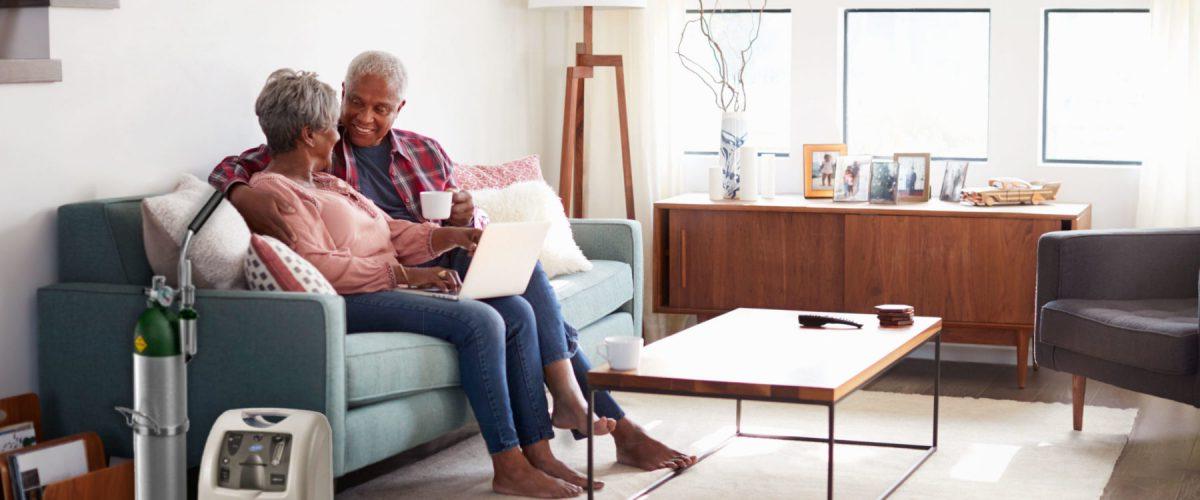 A couple enjoying each other's company on their couch while using an oxygen compressor.